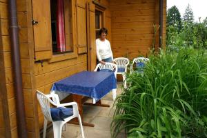 a woman standing on a porch with a table and chairs at Holzhaus im Grünen B&B in Passau
