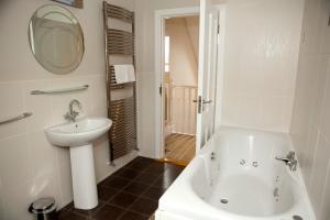 y baño con bañera blanca, lavabo y espejo. en Berehaven Lodge en Castletownbere