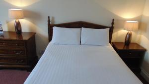 
a neatly made bed with a white comforter at The Harrowgate Hill Lodge in Darlington
