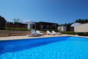 una piscina con sillas y sombrillas junto a una casa en Superior Mobile Homes in Camping Kastanija, en Novigrad Istria