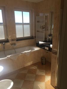 ein Badezimmer mit einer Badewanne, einem WC und einem Waschbecken in der Unterkunft Strandhotel Deichgraf Graal-Müritz in Graal-Müritz