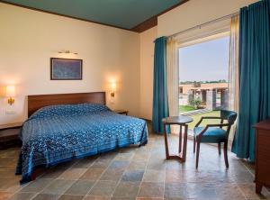 a bedroom with a bed and a table and a window at Dera Masuda Luxury Resort in Pushkar