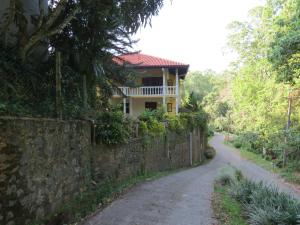 a house on a stone wall next to a road at Hantana Forest Reserve Inn in Kandy