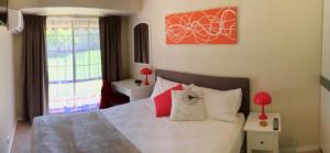 Un dormitorio con una cama blanca con almohadas rojas y blancas en Murdoch Station, en Perth