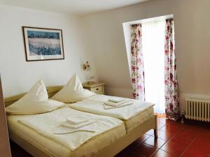 Un dormitorio con una cama con sábanas blancas y una ventana. en Hotel Ratskeller, en Zell an der Mosel