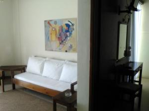 a living room with a white couch and a painting at Aparthotel Iliahtides in Amarynthos