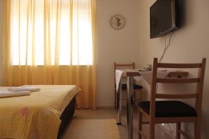 a bedroom with a bed and a table and a television at Apartments and rooms Lena in Mostar
