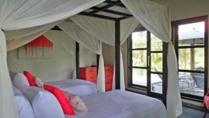 a bedroom with two beds with white sheets and red pillows at Rouge - Private Villa Condense in Ubud