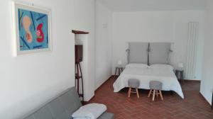 1 dormitorio con 1 cama blanca y 2 taburetes en Podere Le Volte degli Angeli en Spello