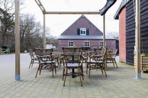 een houten tafel en stoelen op een patio met een gebouw bij In de Hei in Mariahout