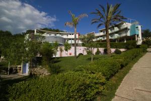 a large white building with palm trees and a sidewalk at Terme Del Tufaro in Contursi