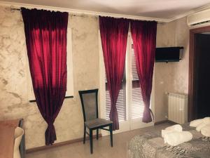 a bedroom with red curtains and a chair and a bed at Hotel Villa Flora in Bogliasco