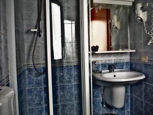 a blue tiled bathroom with a sink and a shower at Hotel Villa Flora in Bogliasco