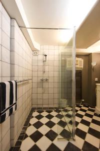 a bathroom with a glass shower with a checkered floor at Studio Sautille in Zandvoort
