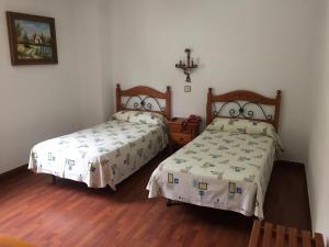 a bedroom with two beds and a cross on the wall at Hostal Pancorbo in Pancorbo