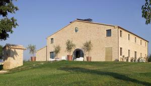un gran edificio de ladrillo situado en lo alto de un exuberante campo verde en Solea Relais di Charme- Adults only, en Trecastelli