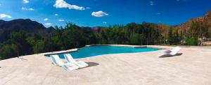 two white chairs sitting on a patio near a swimming pool at Bosque Divino Cabañas & Suites in Valle Grande