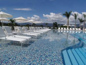 a swimming pool with white lounge chairs and umbrellas at Club Campestre De Bucaramanga in Bucaramanga
