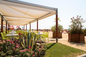 a patio with tables and chairs on the beach at Appartamenti Alaska in Bibione