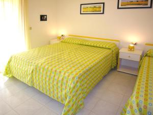 1 dormitorio con 1 cama con colcha amarilla en Appartamenti Alaska en Bibione