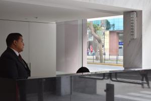 un hombre con traje y corbata parado en un mostrador en Upper Pardo Apartments, en Lima
