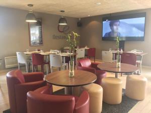 a restaurant with tables and chairs and a screen at Campanile Nantes ~ Saint-Herblain in Saint-Herblain