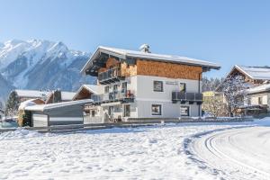 a building in the snow with mountains in the background at Apartmenthaus Maximilian in Neukirchen am Großvenediger