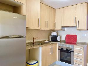 una piccola cucina con armadi in legno e frigorifero di Residencial Tazacorte Luxe a Tazacorte