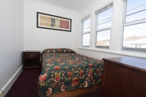 a bedroom with a bed with a floral bedspread and two windows at Shore Beach Houses - 119 F Franklin Avenue in Seaside Heights