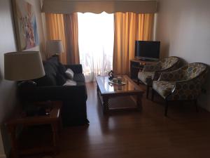 a living room with a couch and chairs and a television at Apartamento Edificio Genova in Viña del Mar +4 photos