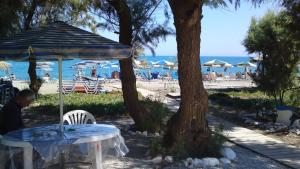 a man sitting at a table under an umbrella at the beach at Gradma Katina in Platanias