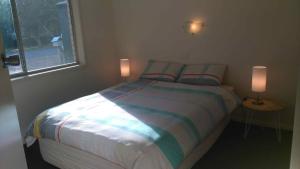 a bedroom with a bed with two lamps on it at Ageri Holiday Unit in Bright