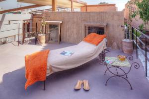un grande letto con lenzuola arancioni, un tavolo e scarpe di Riad Carina a Marrakech