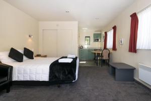 um quarto com uma cama grande e uma mesa em Ashleigh Court Motel em Blenheim