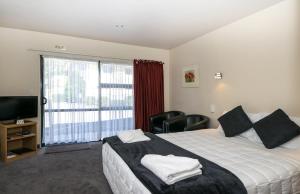 a hotel room with a bed and a large window at Ashleigh Court Motel in Blenheim
