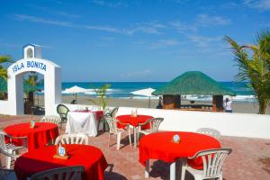 Isla Bonita Beach Resort في سان خوان: مطعم به طاولات حمراء وكراسي على الشاطئ