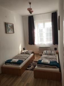 two beds in a room with a window at Éva Apartman in Miskolc