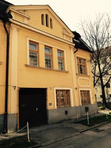 un bâtiment jaune avec une porte noire dans une rue dans l'établissement Éva Apartman, à Miskolc