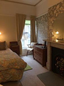 a bedroom with a bed and a fireplace and a window at Riverside Guest House in Morpeth