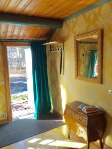 Zimmer mit einem Spiegel, einem Tisch und einer Tür in der Unterkunft Olsbacka cottage in Falun