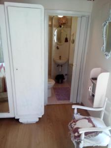a white bathroom with a toilet and a chair at Lunartista in Varazze