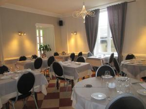 a restaurant with white tables and chairs and a window at Logis Hostellerie Du Cheval Blanc in Sainte-Maure-de-Touraine