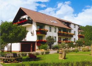 維岑豪森的住宿－Dorf gut Hotel zur Warte，一座大白色的建筑,在院子里种着鲜花
