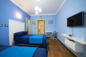 a blue room with two beds and a flat screen tv at B&B 'O Sole Mio! in Naples