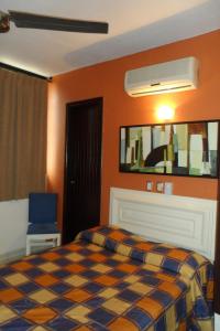 a bedroom with a bed and a blue chair at Hotel Fernando in Tuxtla Gutiérrez