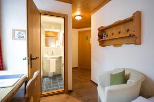 a room with a white chair and a bathroom at Sporthotel Victoria in Gstaad