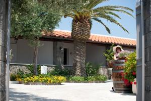une femme debout à côté d'un palmier devant une maison dans l'établissement Residence Le Vigne, à Ischia