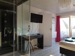 a bedroom with a glass shower with a desk and a television at B&B Acacia in Goirle