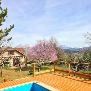 une grande terrasse en bois avec vue sur une maison dans l'établissement Villa à Gap, à Gap