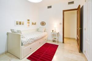 グラナダにあるAFAN Granada y PARKING incluidoの白いベッドルーム(ベッド1台、赤い敷物付)